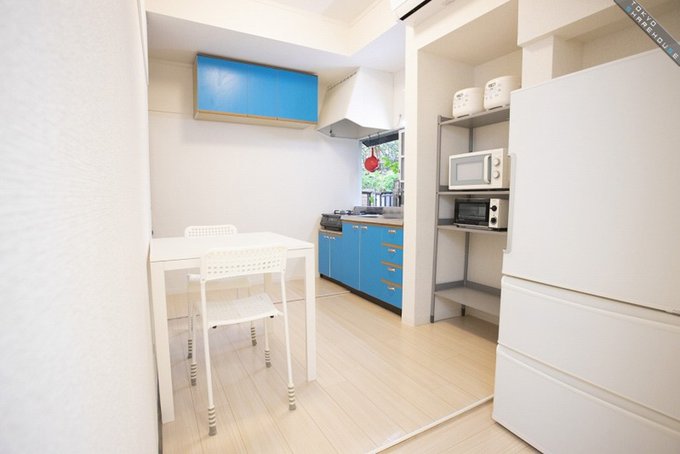 白いコンパクトなスペースの一角。ブルーが印象的な奥の横壁面と正面に収納棚があり、初めての一人暮らしに向いた女子の部屋のような雰囲気。