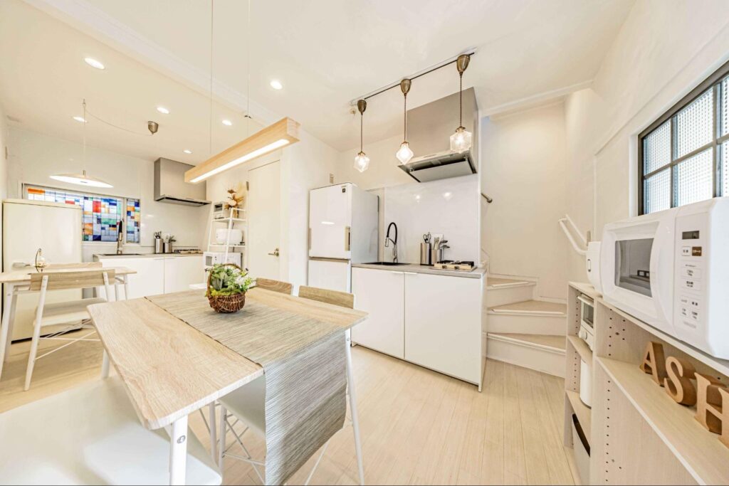 右奥にらせん階段があり二階へ続いている。ウッド調のダイニングテーブルがアクセントになり、温かみのある雰囲気。