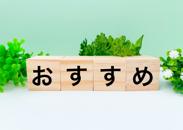 グリーンの背景に葉っぱがちらほらと描かれ、その前に木の正方形のブロックが並んでいる。ブロックには黒字で一文字ずつ『おすすめ』と日本語で書かれていて、全体で『おすすめ』の文字列を形づくっている。