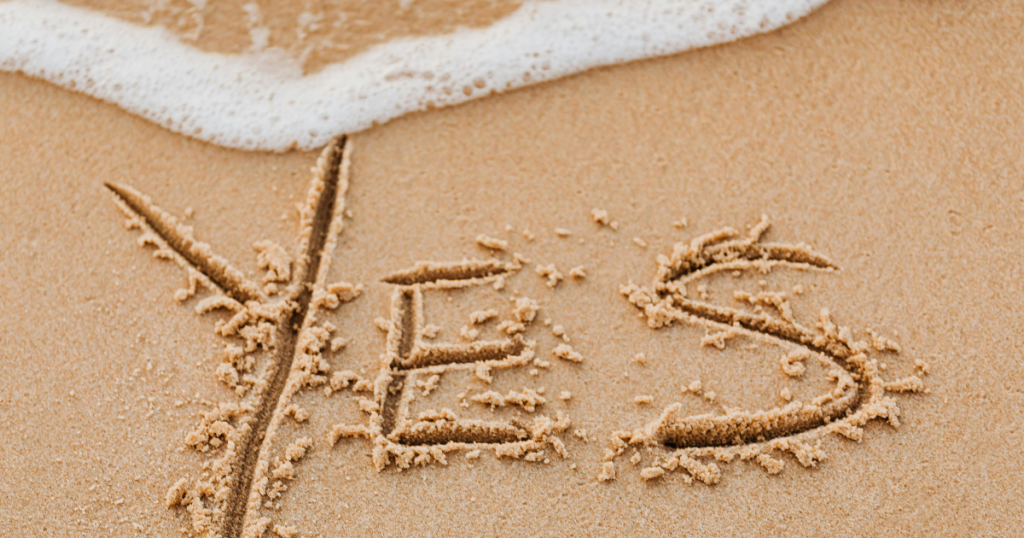 波がうっすらと打ち寄せる砂浜に、英語で『YES』と書かれている文字が見える。